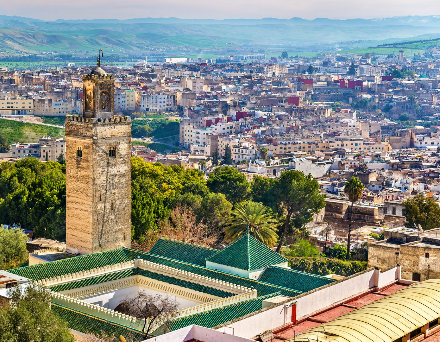 Scenic cityscape with historic tower and lush greenery under a clear sky.