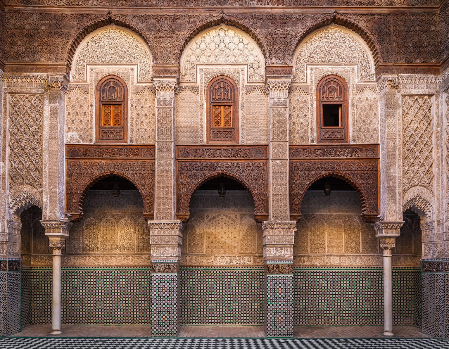 Intricately designed arches and tiled walls in a historic building courtyard.
