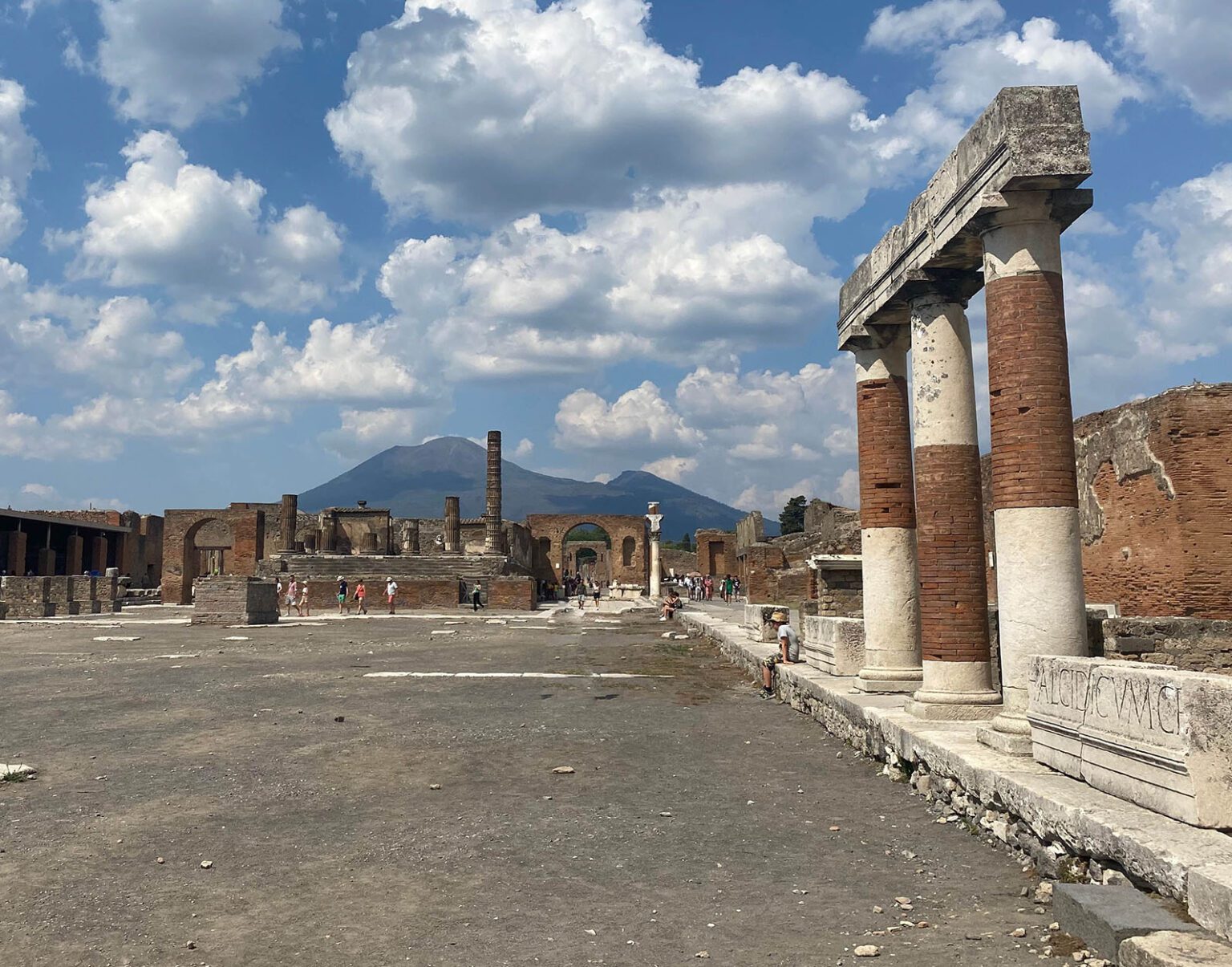 Ancient ruins under a blue sky with scattered clouds.