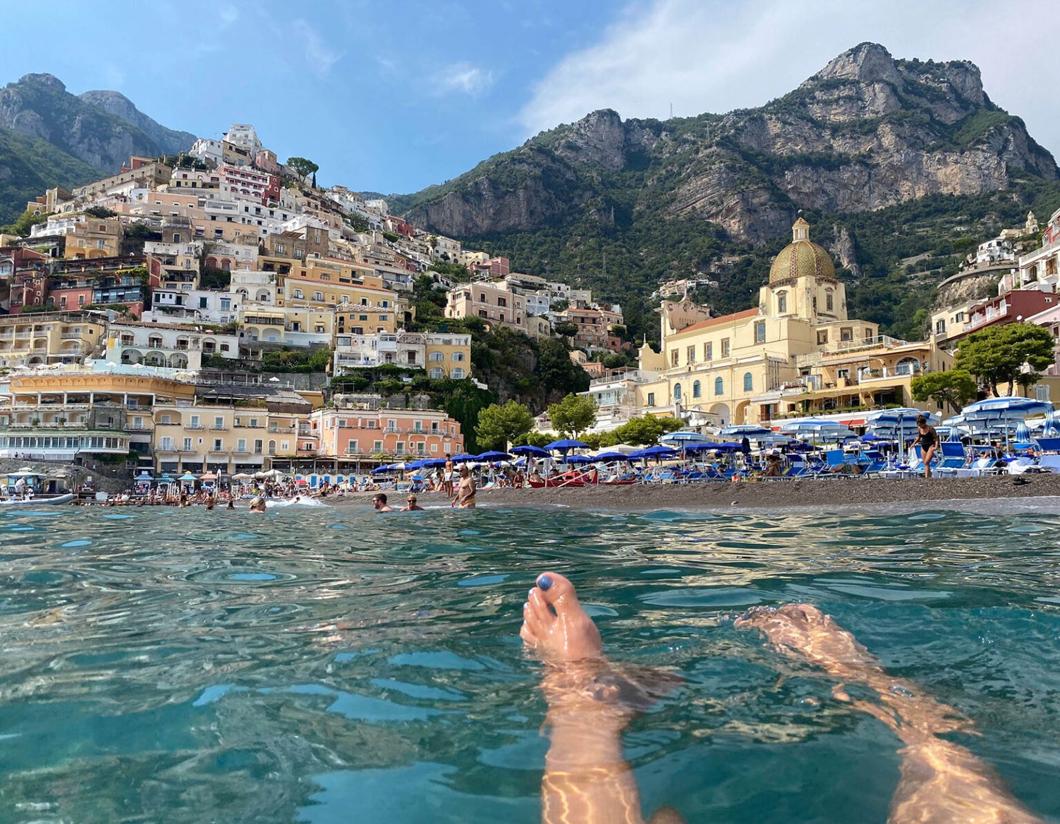 Relaxing in clear water with a coastal town and mountains in the background.