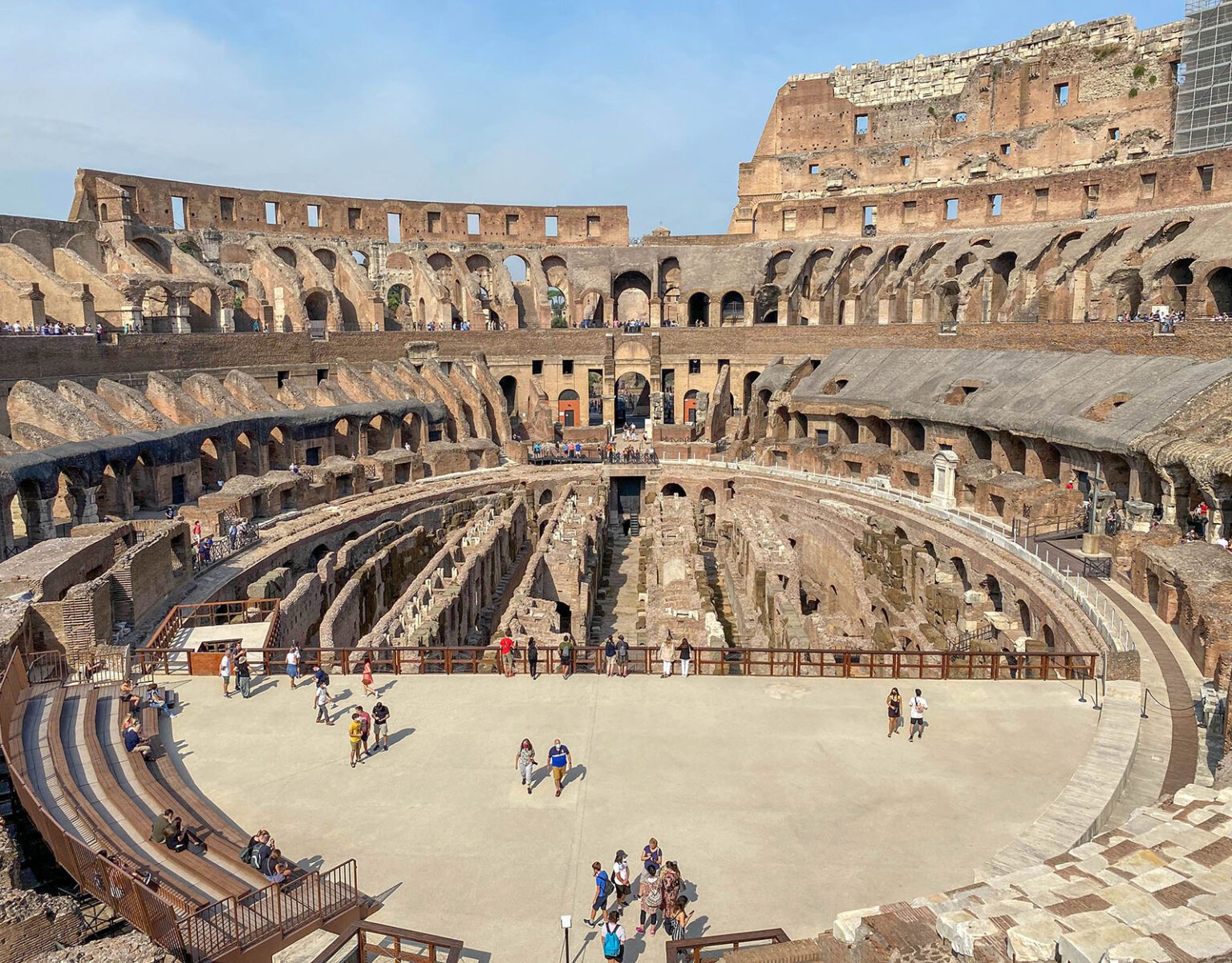 Interior view of the ancient Roman Colosseum with visitors exploring.