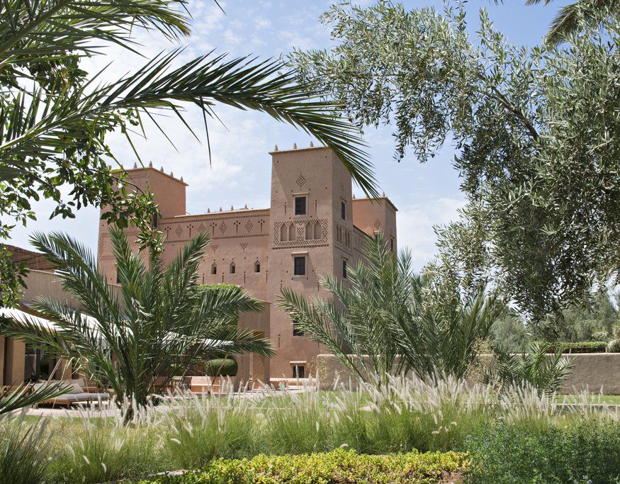 Historic brick fortress surrounded by lush greenery and palm trees.