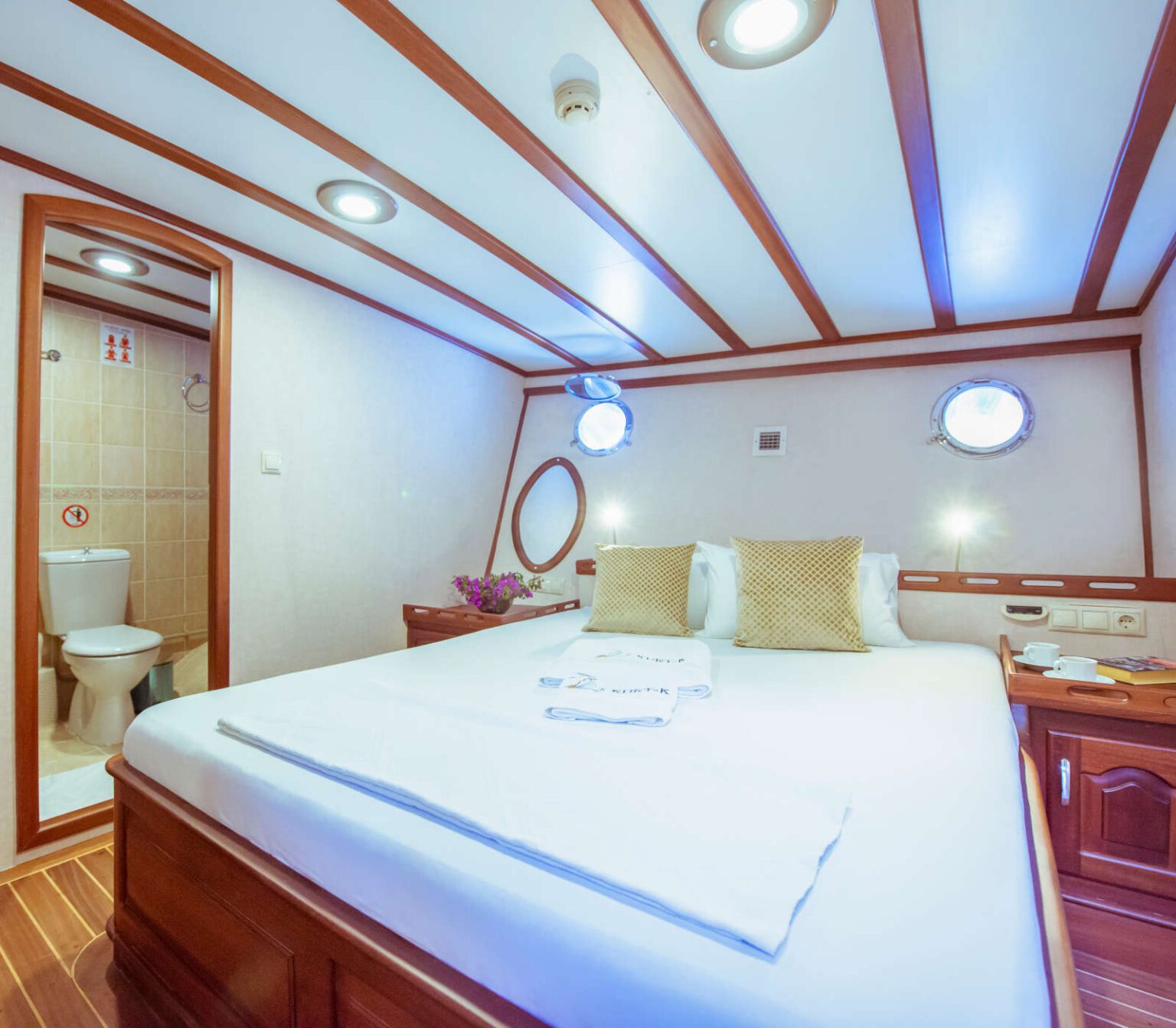 Cozy yacht cabin with wooden accents and round windows.