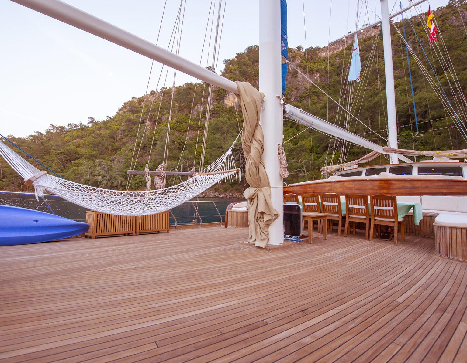 A hammock hanging on a wooden deck with scenic hills in the background.