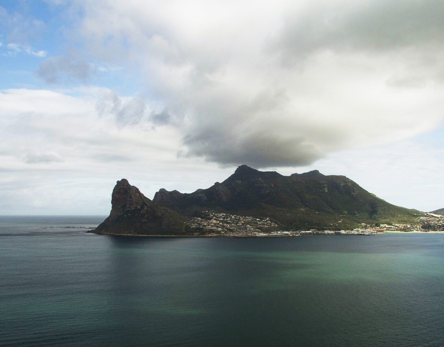 A rocky island under a cloudy sky surrounded by calm waters.