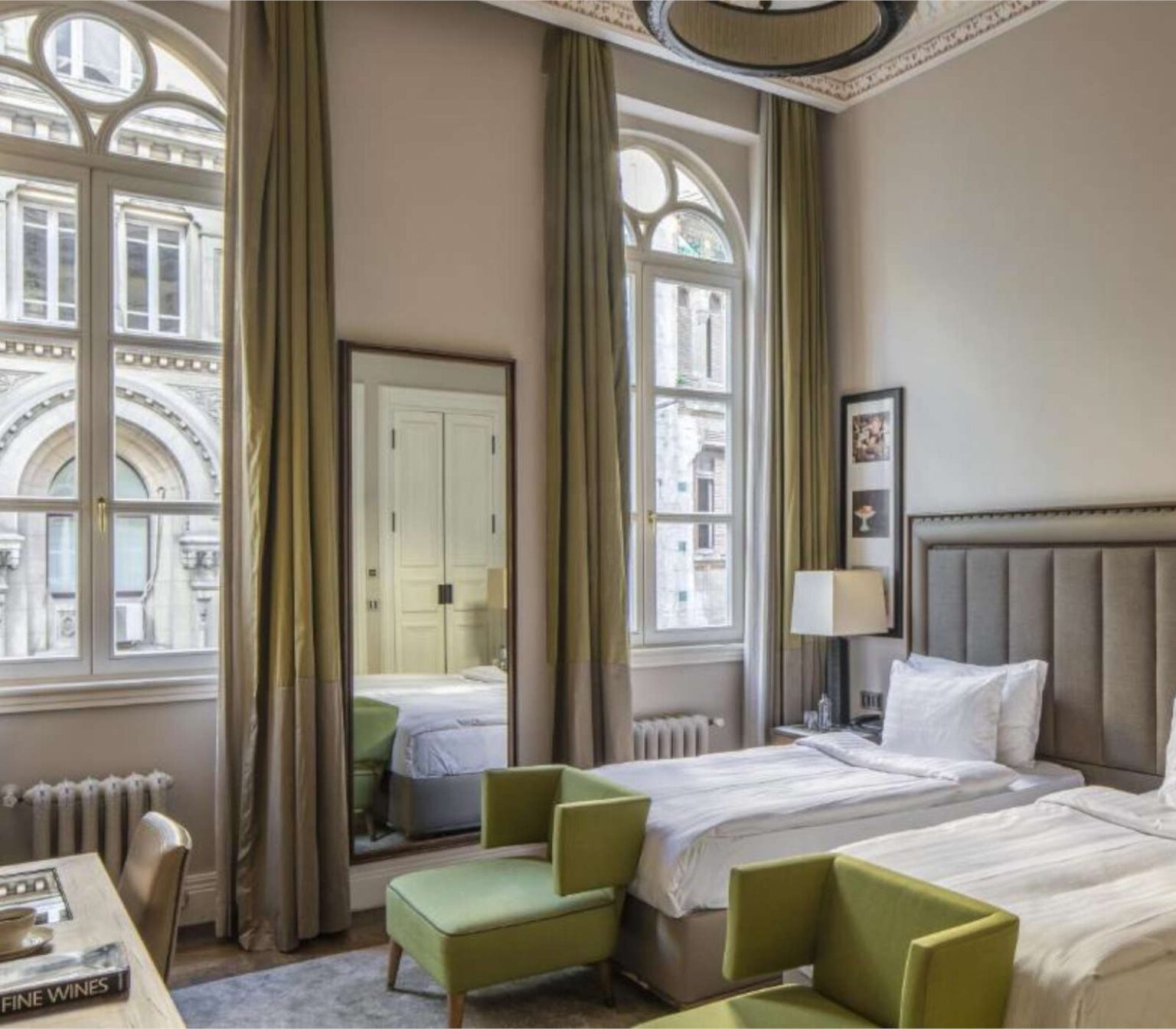 Elegant hotel room with twin beds and tall windows.