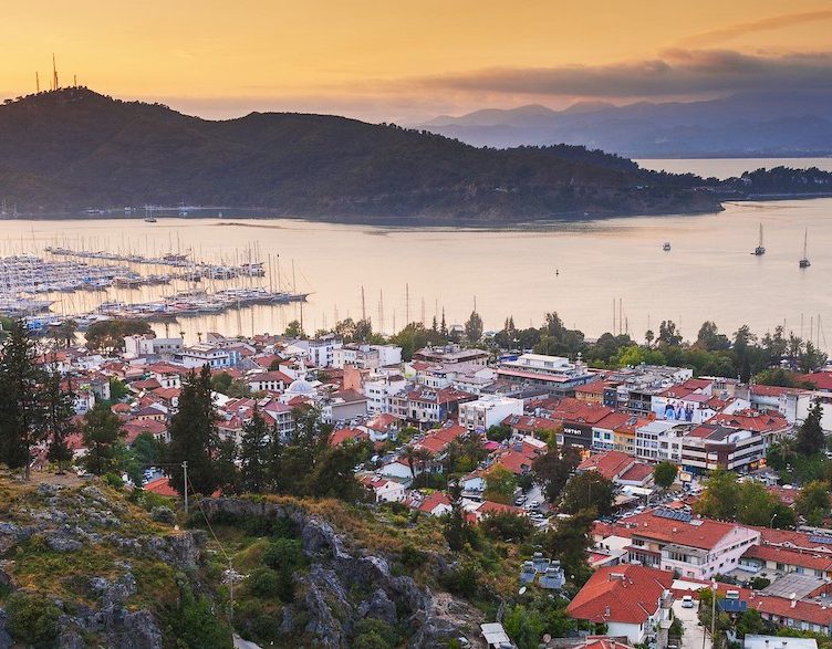 Scenic coastal town with red-roofed houses at sunset.