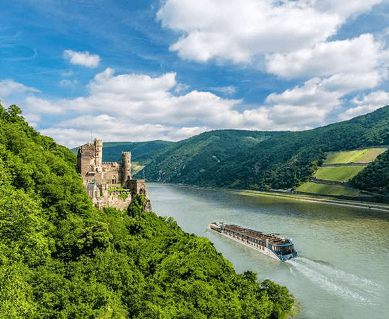 A boat sailing on a river with a castle and lush green hills around.