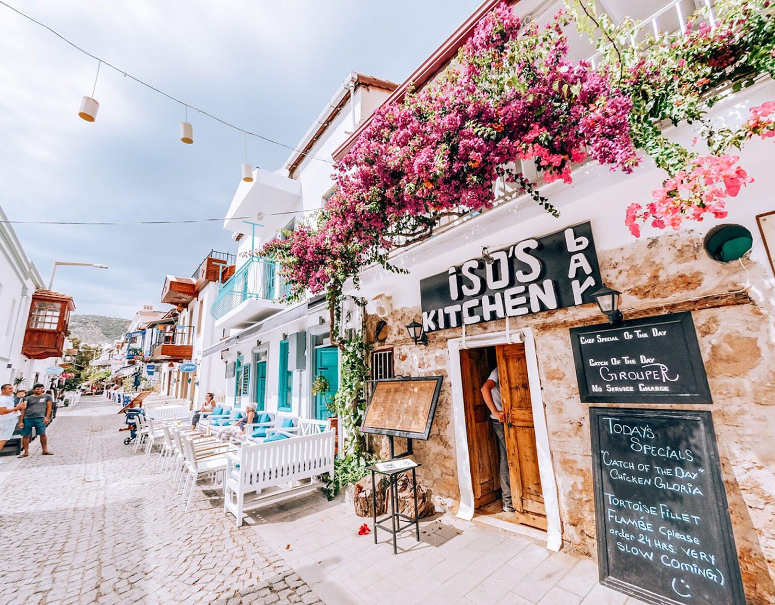 Charming street with colorful buildings and vibrant pink flowers above a kitchen entrance.