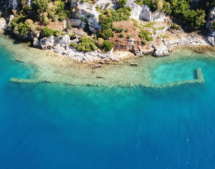 Aerial view of a rocky coastline with clear turquoise water.