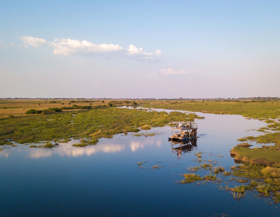 A boat sailing on a calm river surrounded by green marshlands.