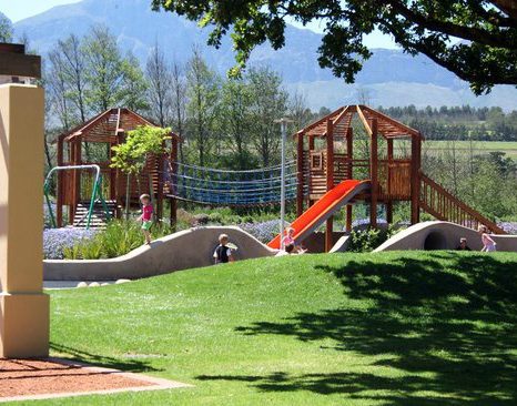 Children playing on a wooden playground with slides and climbing structures.