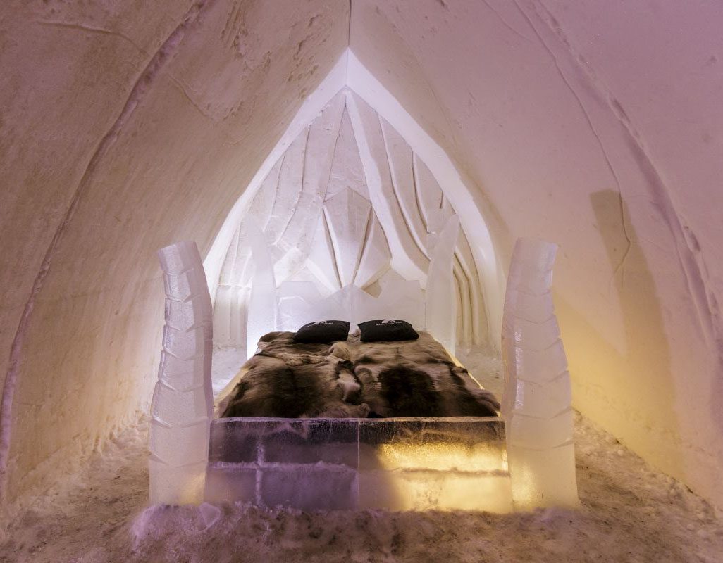 Cozy bed inside an intricately carved ice structure.