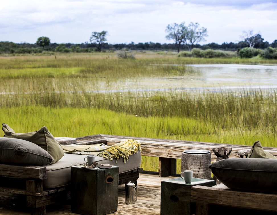 Rustic outdoor kitchen by a serene lake with green reeds.