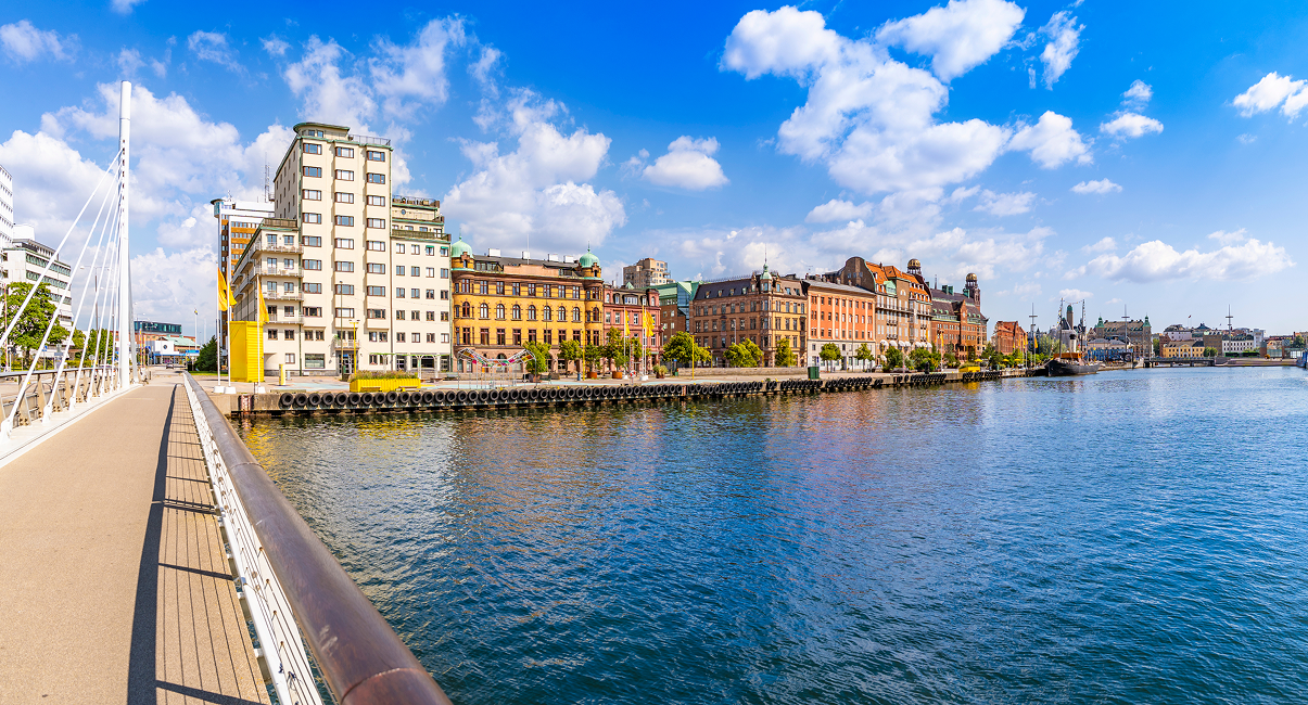 Scenic waterfront with historic buildings under a bright blue sky.