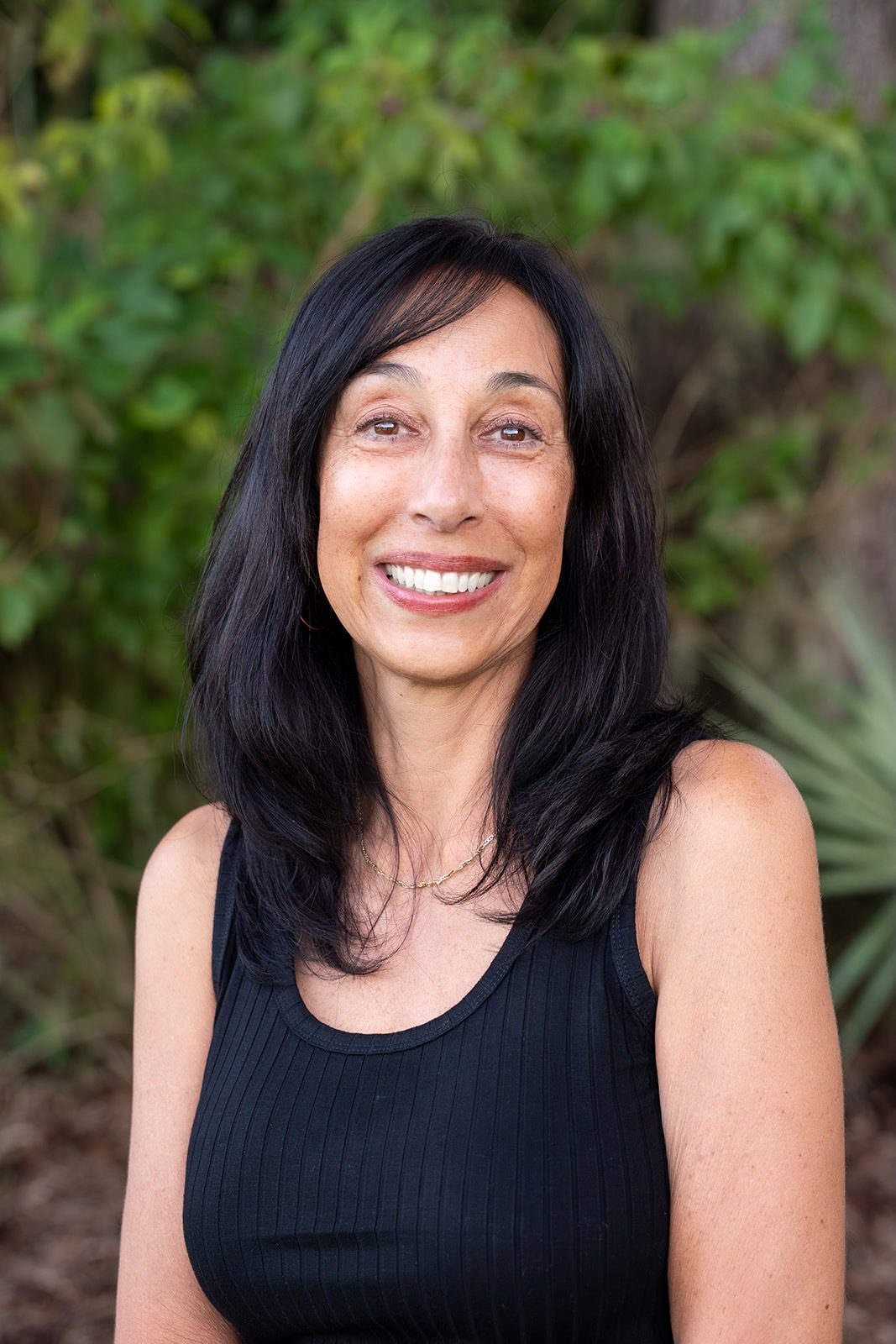 Smiling woman with long black hair outdoors.