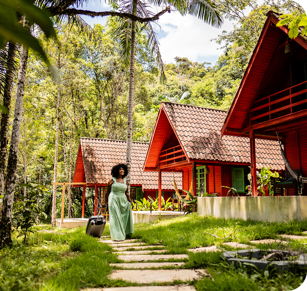Person walking near red cottages in a forested area.