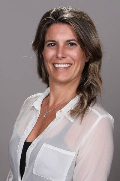 Smiling woman in a white blouse with wavy hair.