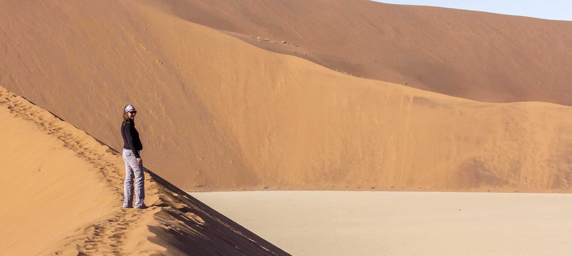 Expansive sand dunes under clear sky in a desert landscape.