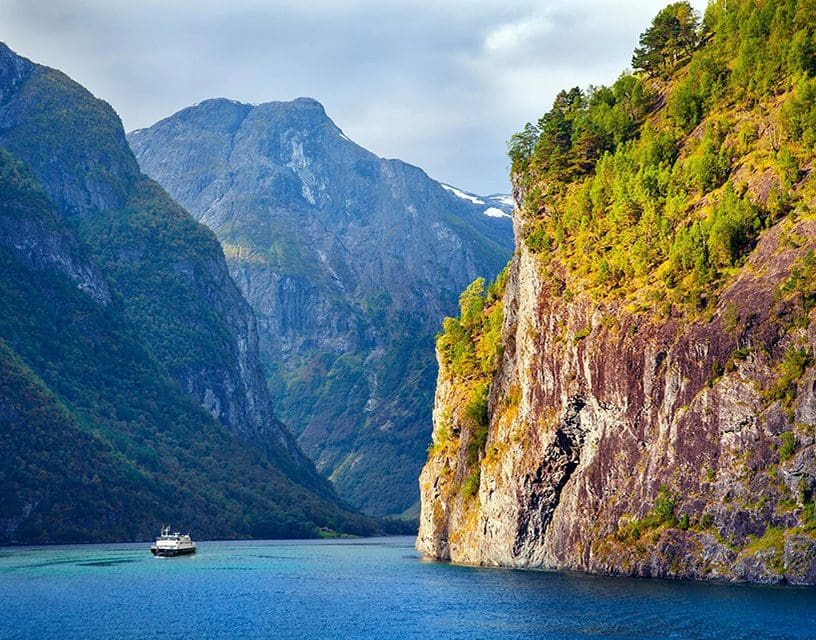 Boat in Norwegian fjord with towering cliffs
