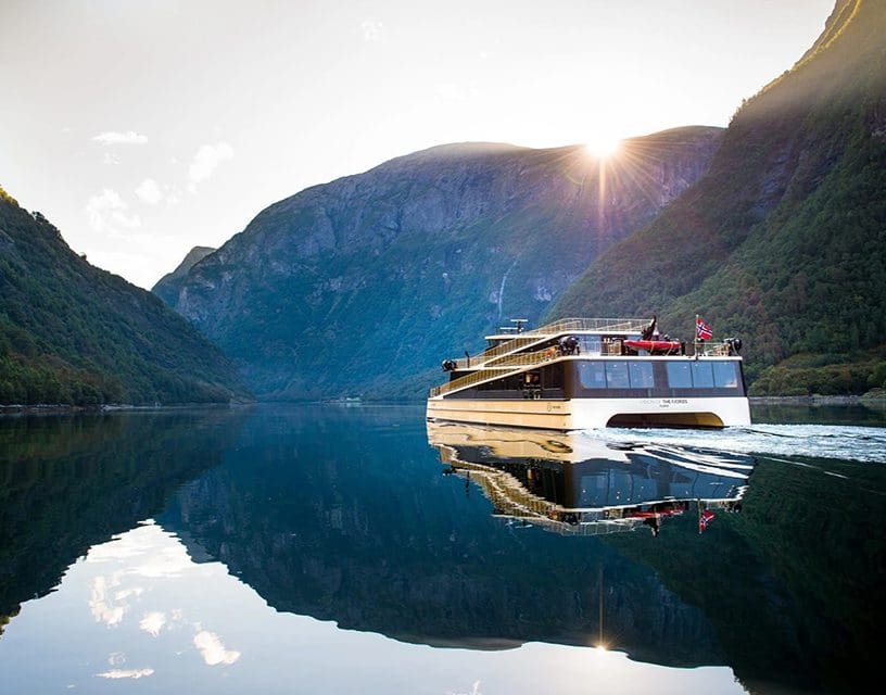 Tour boat reflected on calm fjord water