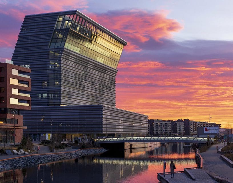 Modern waterfront building and bridge at sunset
