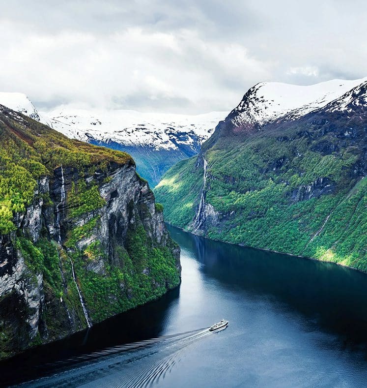 Boat cruising through scenic snow-capped fjord